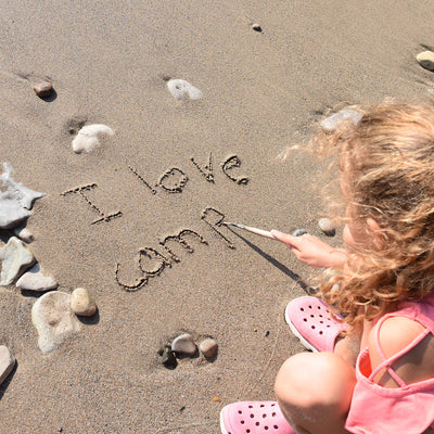 A child writing in the sand.