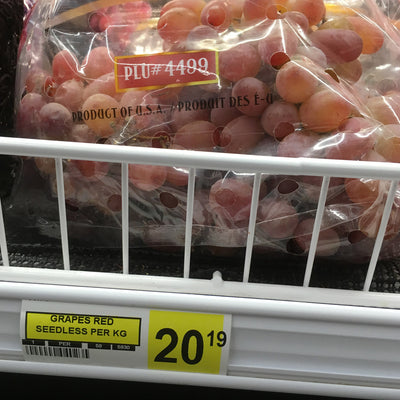 A grocery store shelf with red grapes priced at $20.19 per kilogram.
