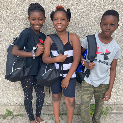 Three children holding backpacks.