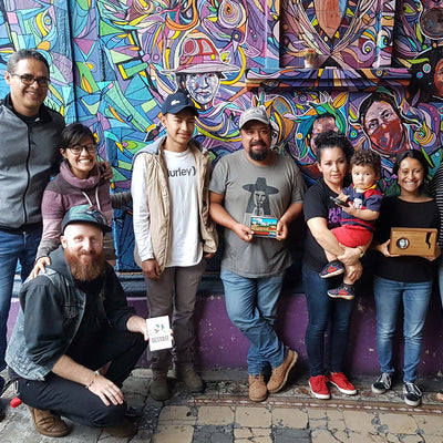 A group of adults and children standing in front of a mural.