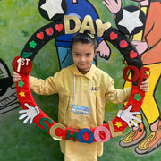 A child holding a wreath that says "First day of school."